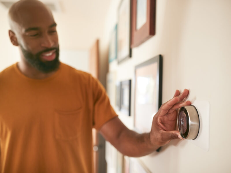 adult adjusting the thermostat of the new smart HVAC system in their home